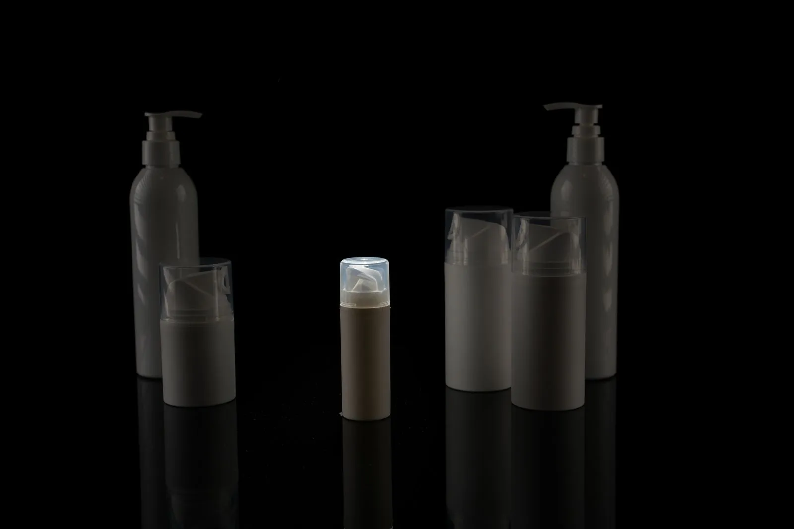 A collection of empty cosmetic bottles on a black background, captured in a minimalist style.